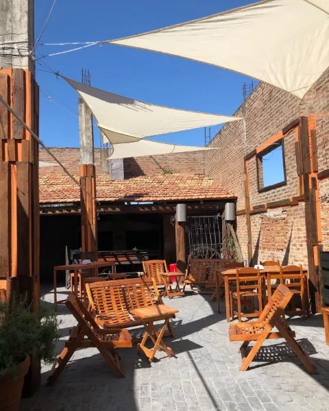Patio al aire libre con mesas de madera y velas de sombra
